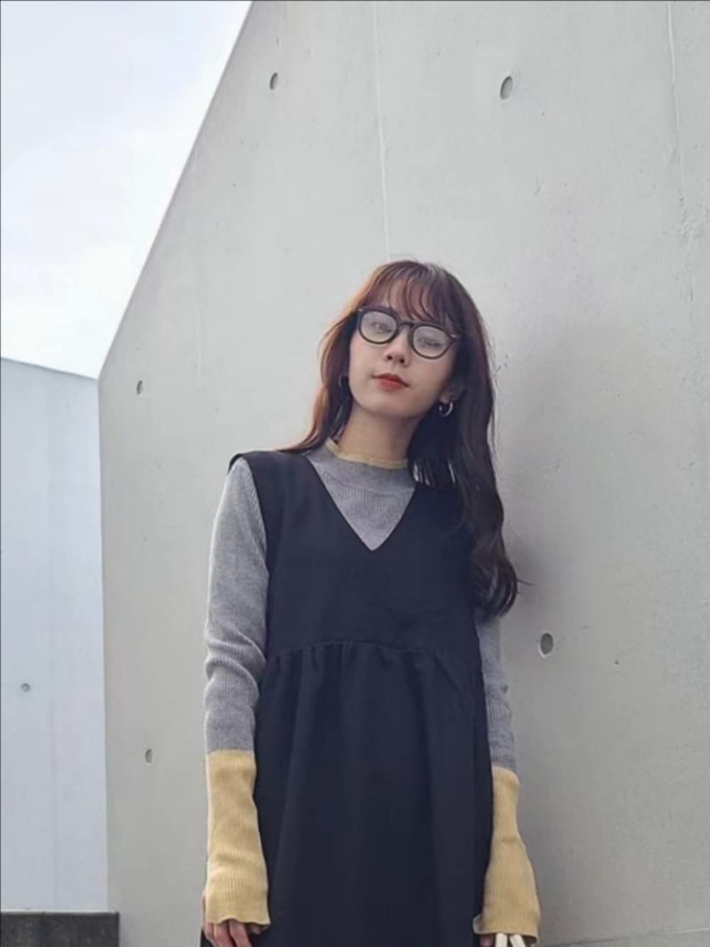 グレー系のニット/セーター、ブラック系のブーツ、ブラック系のジャンパースカートを着用したレディースの冬コーディネートの4枚目の写真