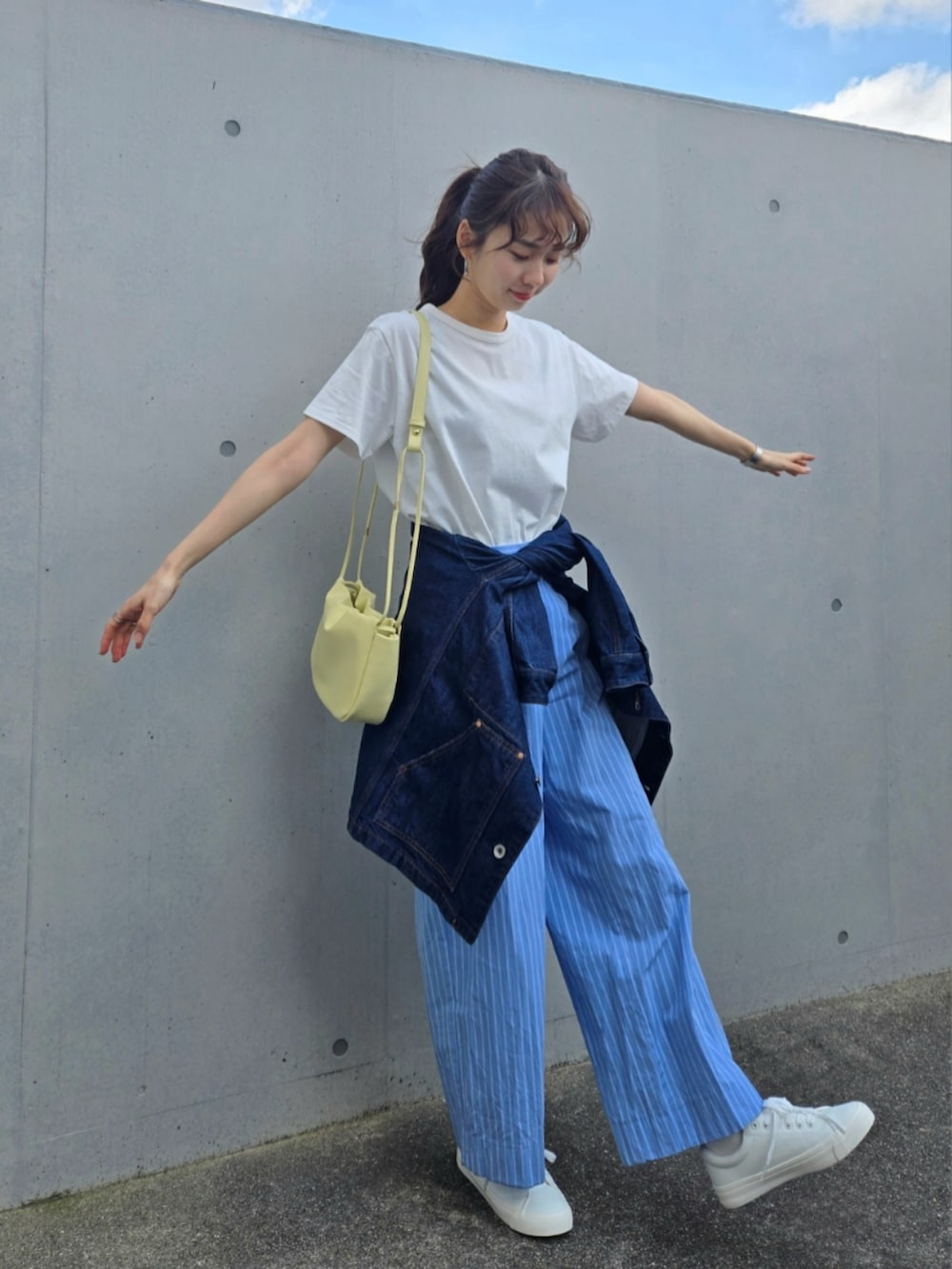 ホワイト系のTシャツ/カットソー、ブルー系のパンツ、イエロー系のショルダーバッグを着用したレディースの春コーディネートの2枚目の写真