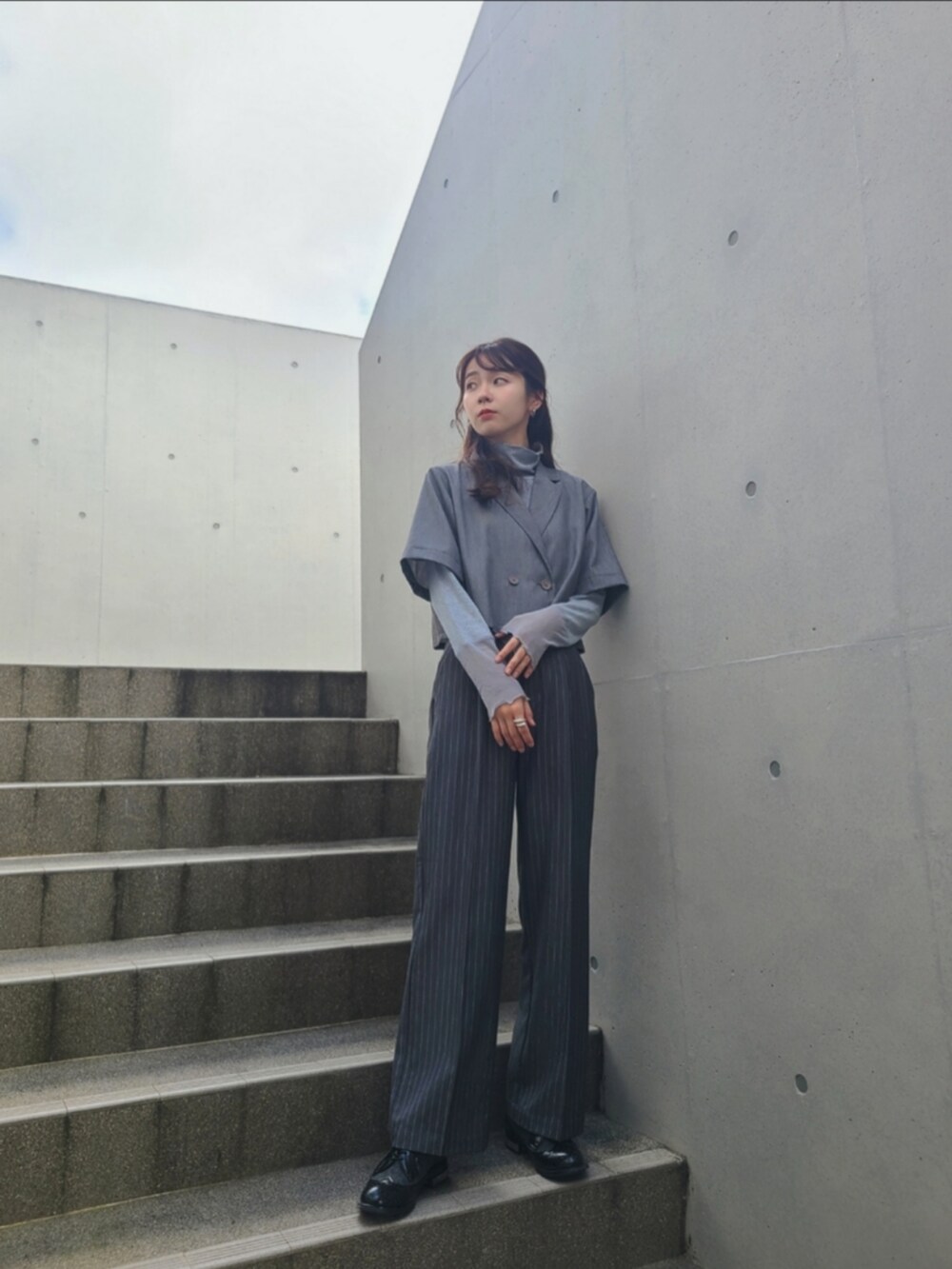 グレー系のスラックス、グレー系のセットアップ、ブルー系のTシャツ/カットソーを着用したレディースの秋コーディネートの3枚目の写真