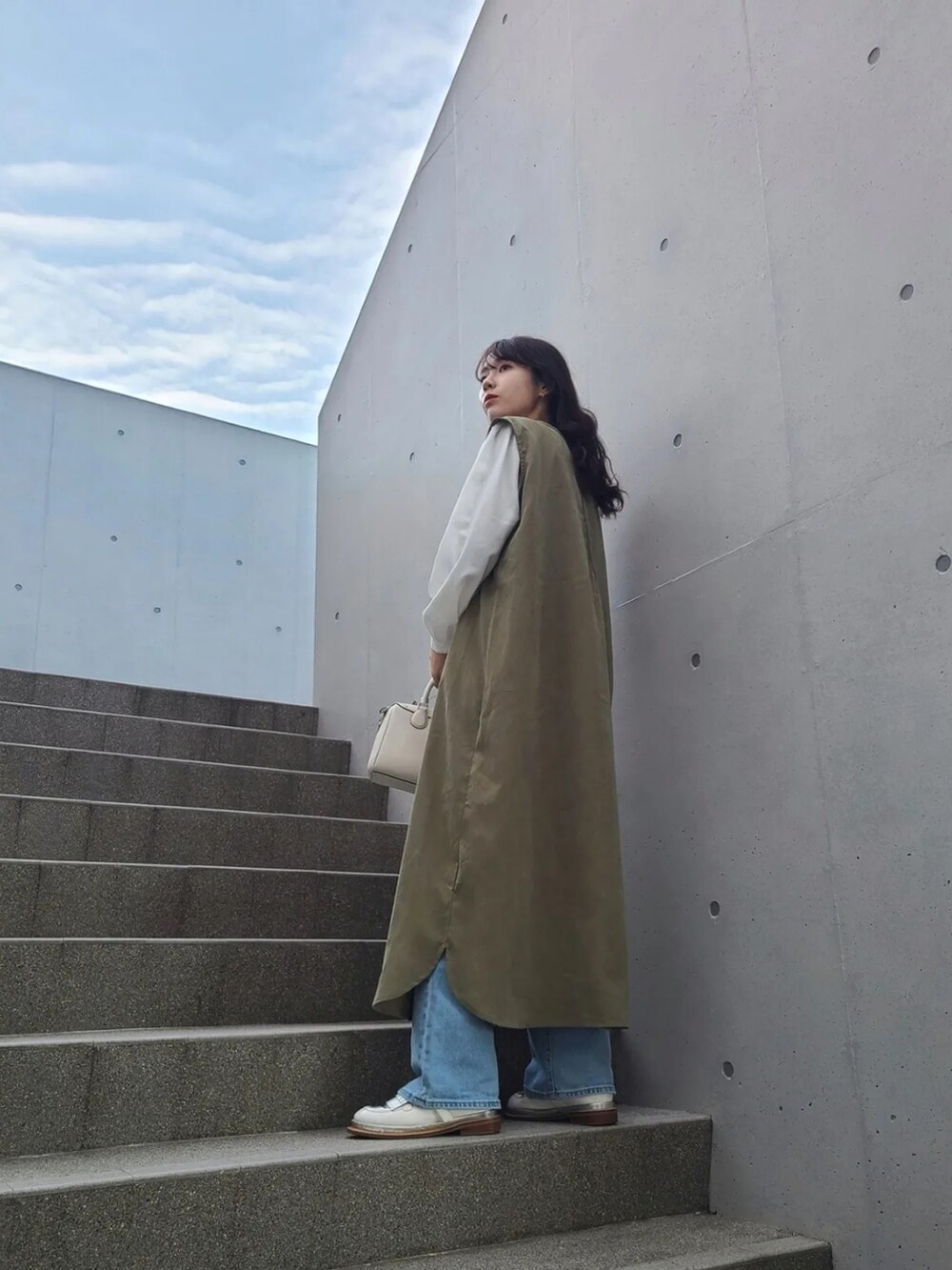 グリーン系のワンピース、ホワイト系のシャツ/ブラウス、ブルー系のデニムパンツを着用したレディースの冬コーディネートの2枚目の写真