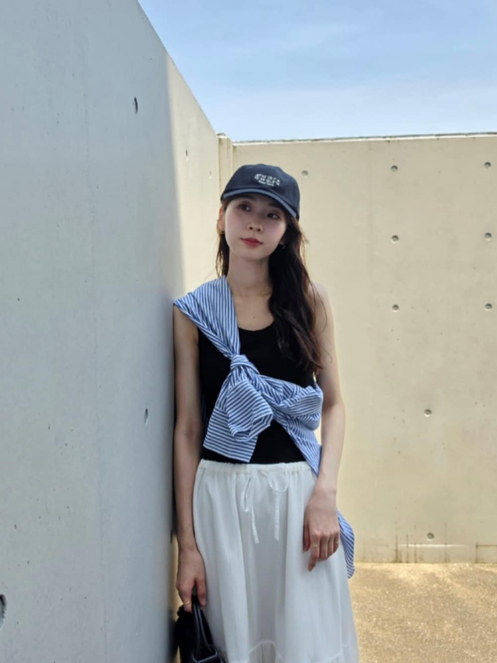 ブルー系のシャツ/ブラウス、ホワイト系のスカート、ブラック系のハンドバッグを着用したレディースの夏コーディネートの3枚目の写真