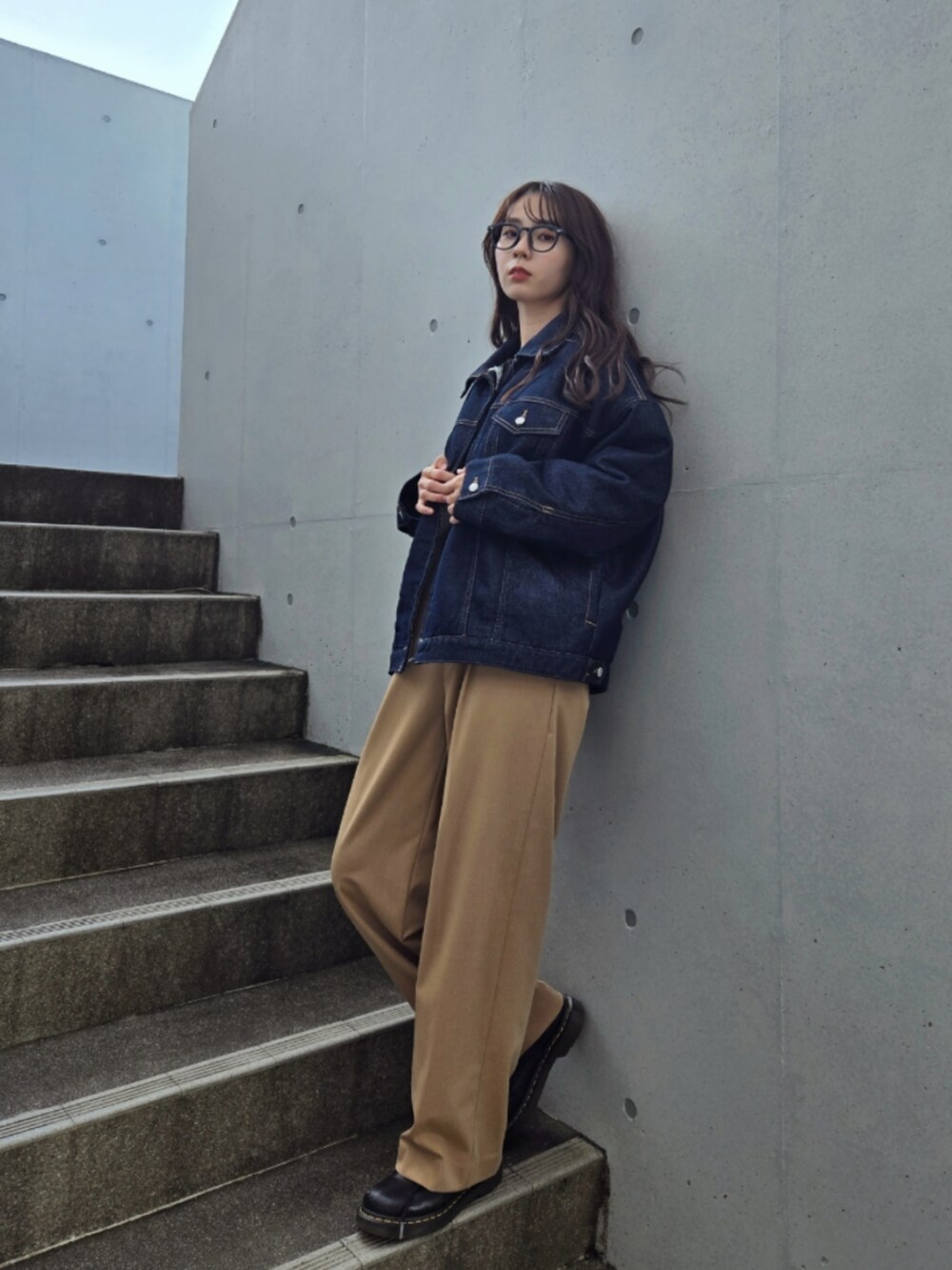 ブルー系のデニムジャケット、ベージュ系のパンツ、ブラック系のブーツを着用したレディースの秋コーディネートの2枚目の写真