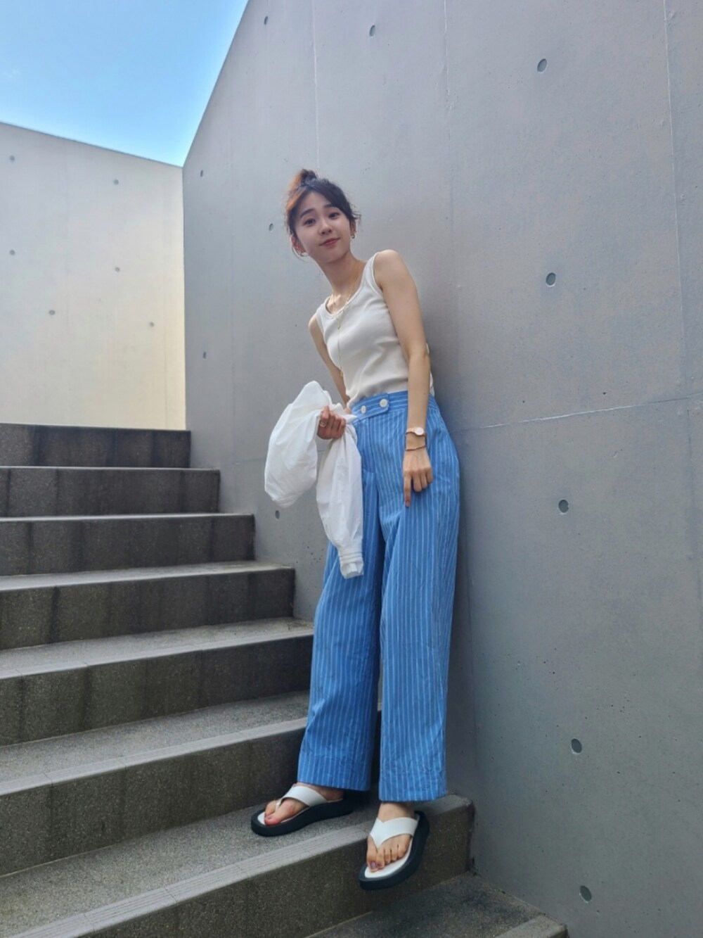 ブルー系のパンツ、ホワイト系のサンダル、ゴールド系のネックレスを着用したレディースの夏コーディネートの2枚目の写真