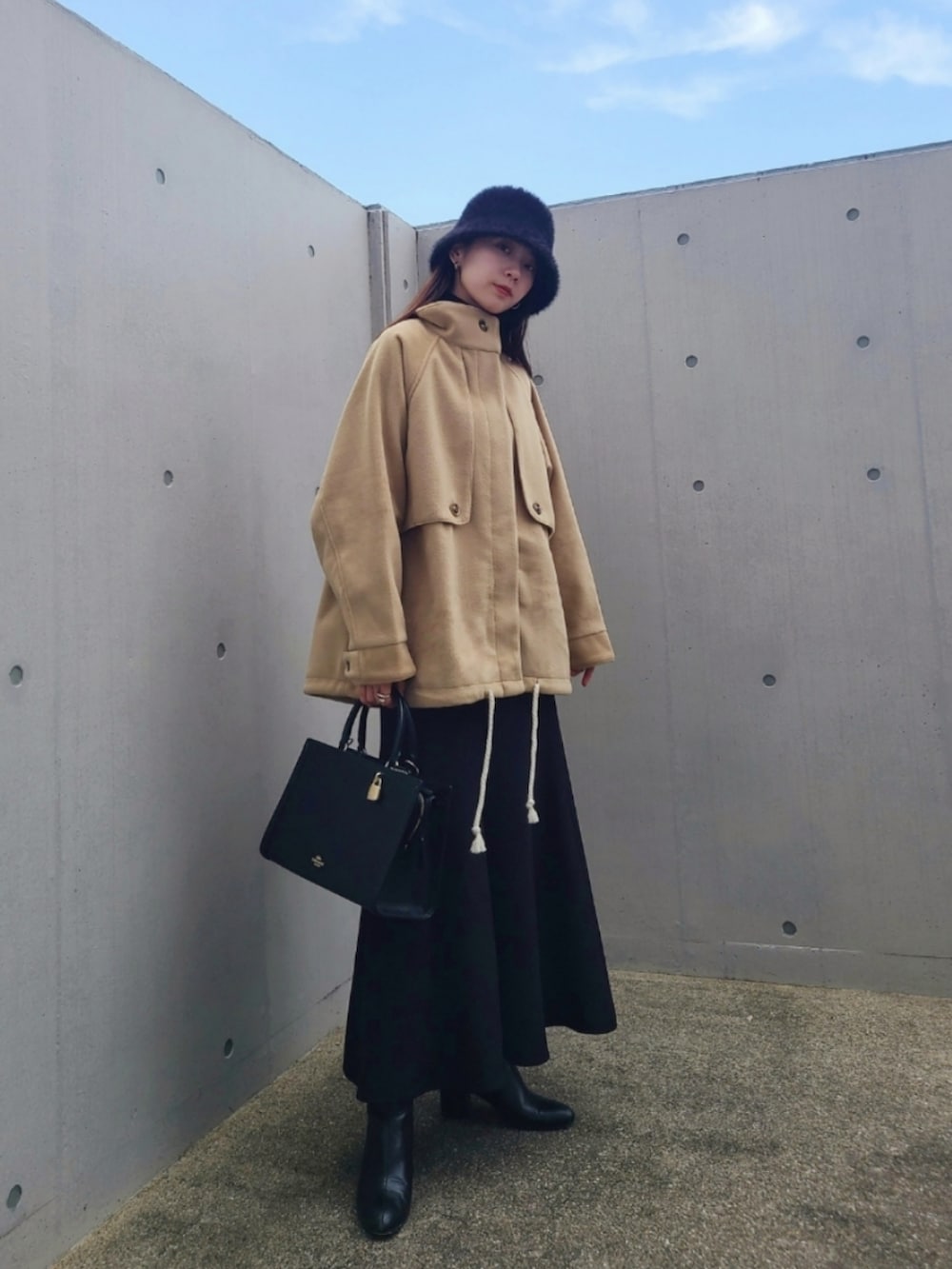 ブラック系のバッグ、ブラック系のブーツ、ベージュ系のその他アウターを着用したレディースの秋コーディネートの3枚目の写真