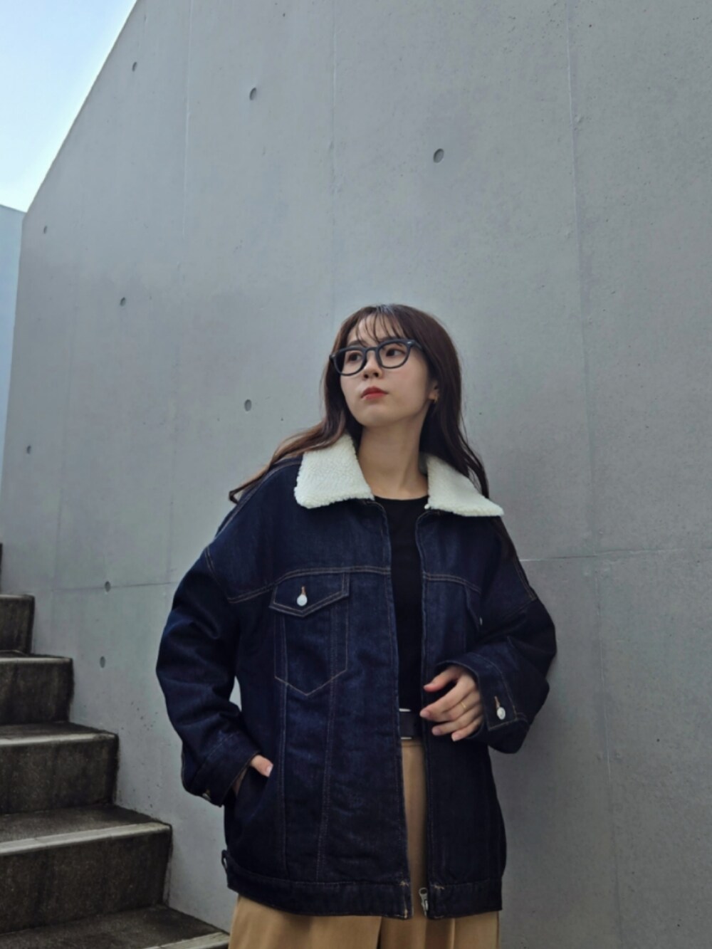 ブルー系のデニムジャケット、ベージュ系のパンツ、ブラック系のブーツを着用したレディースの秋コーディネートの3枚目の写真