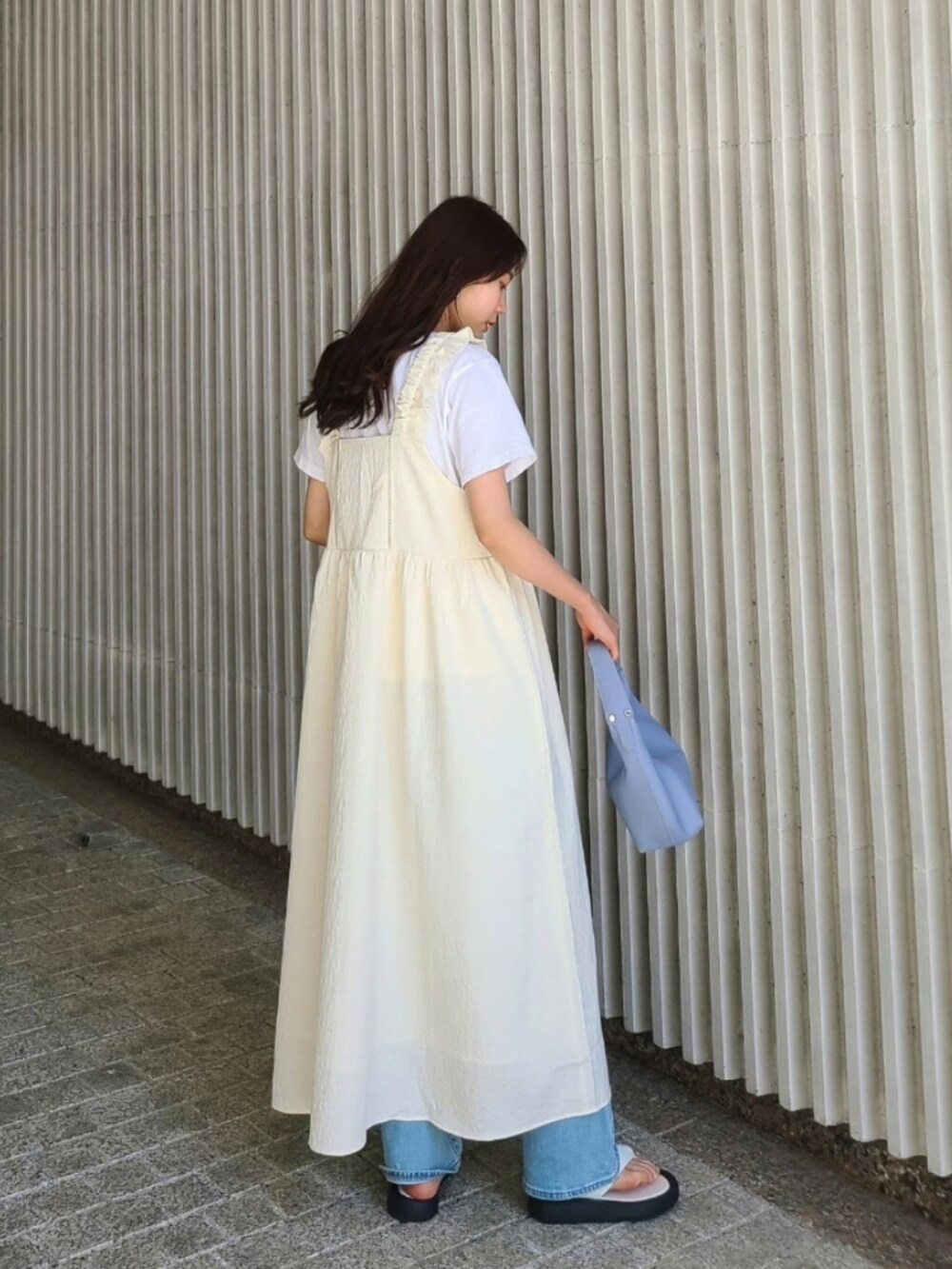 ブルー系のハンドバッグ、ホワイト系のワンピース、ブルー系のデニムパンツを着用したレディースの春コーディネートの2枚目の写真