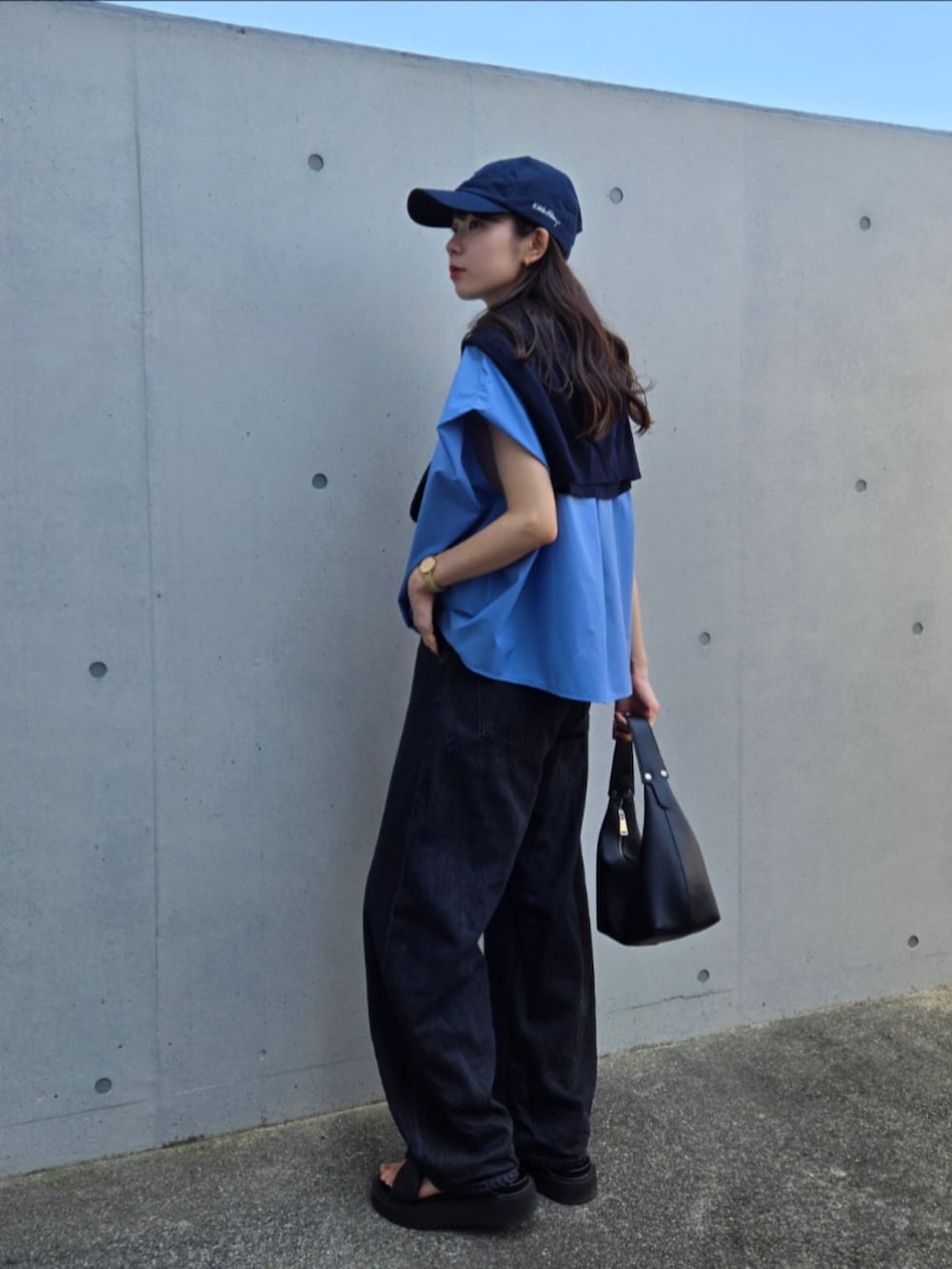 ブラック系のハンドバッグ、ブラック系のデニムパンツ、ブルー系のニット/セーターを着用したレディースの秋コーディネートの2枚目の写真