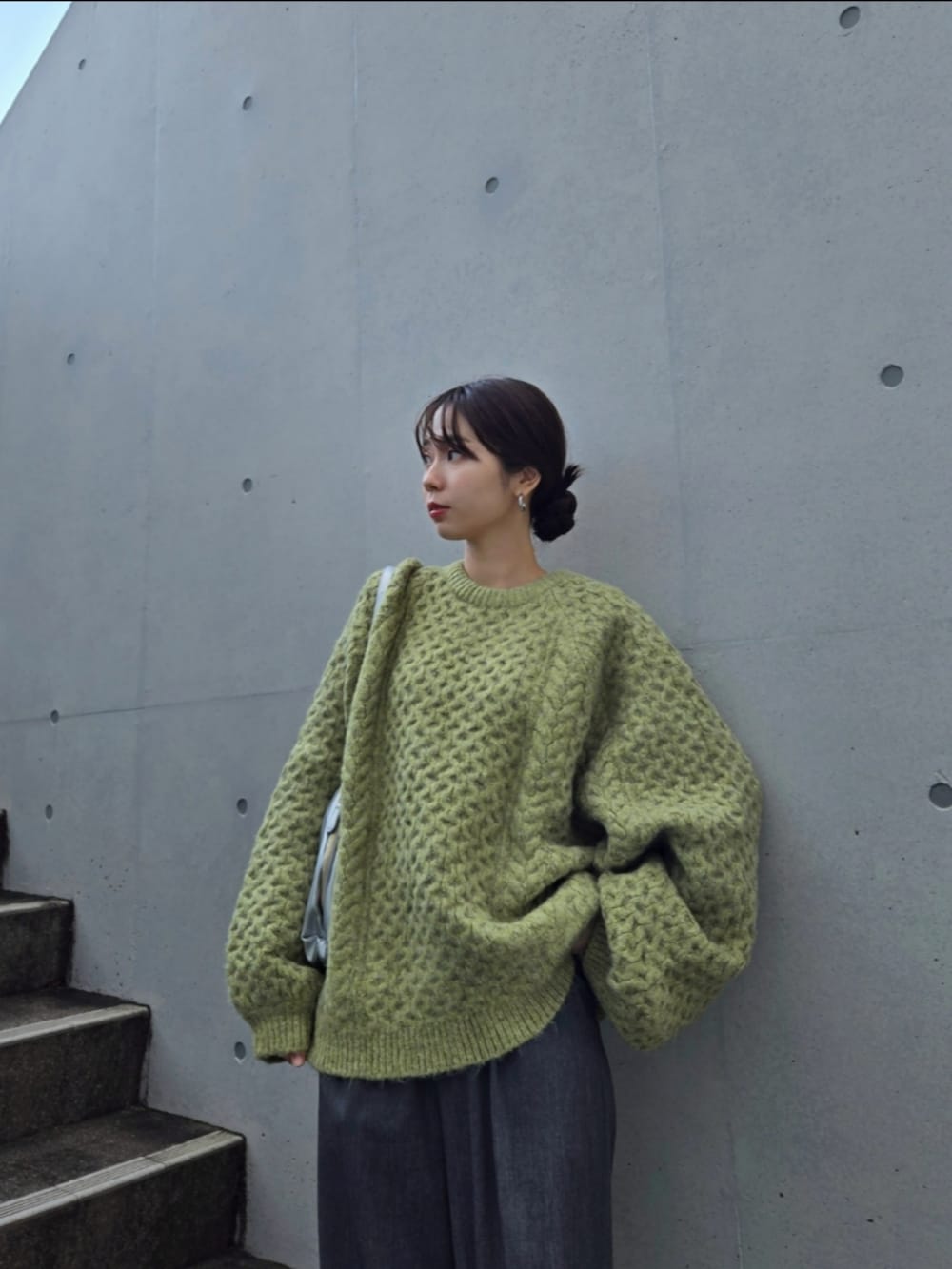 グリーン系のニット/セーター、グレー系のパンツ、シルバー系のハンドバッグを着用したレディースの秋コーディネートの3枚目の写真