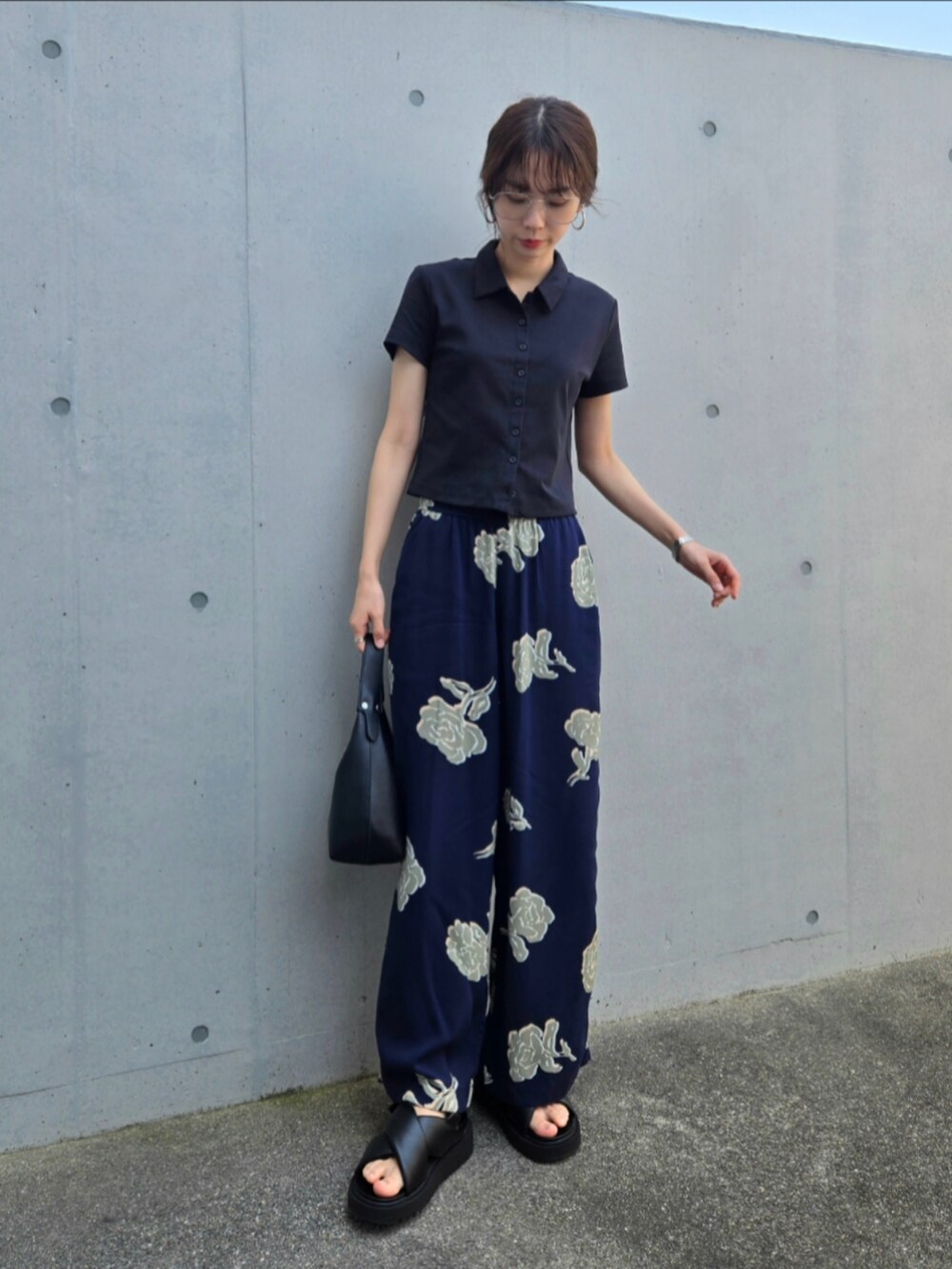 ブラック系のサンダル、ブラック系のハンドバッグ、ブラック系のポロシャツを着用したレディースの夏コーディネートの2枚目の写真