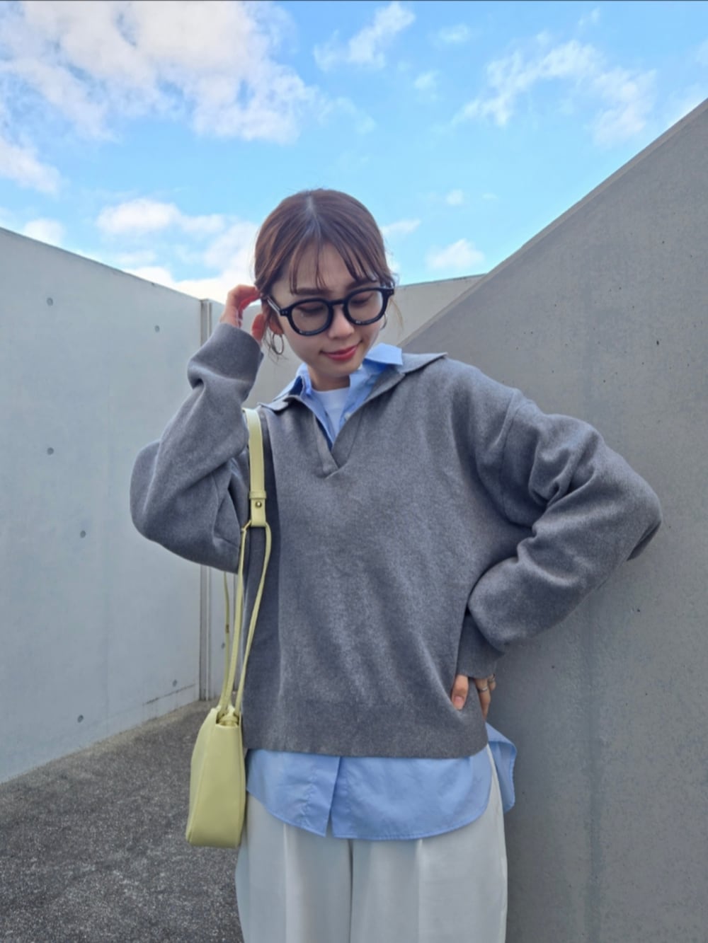 グレー系のニット/セーター、ホワイト系のトップス、イエロー系のショルダーバッグを着用したレディースの春コーディネートの2枚目の写真