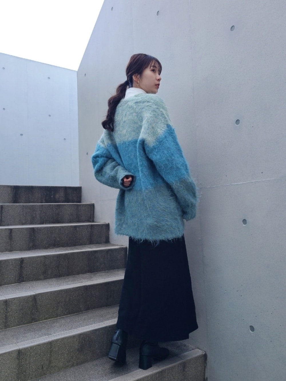 ブルー系のカーディガン/ボレロ、ブラック系のブーツを着用したレディースの冬コーディネートの2枚目の写真