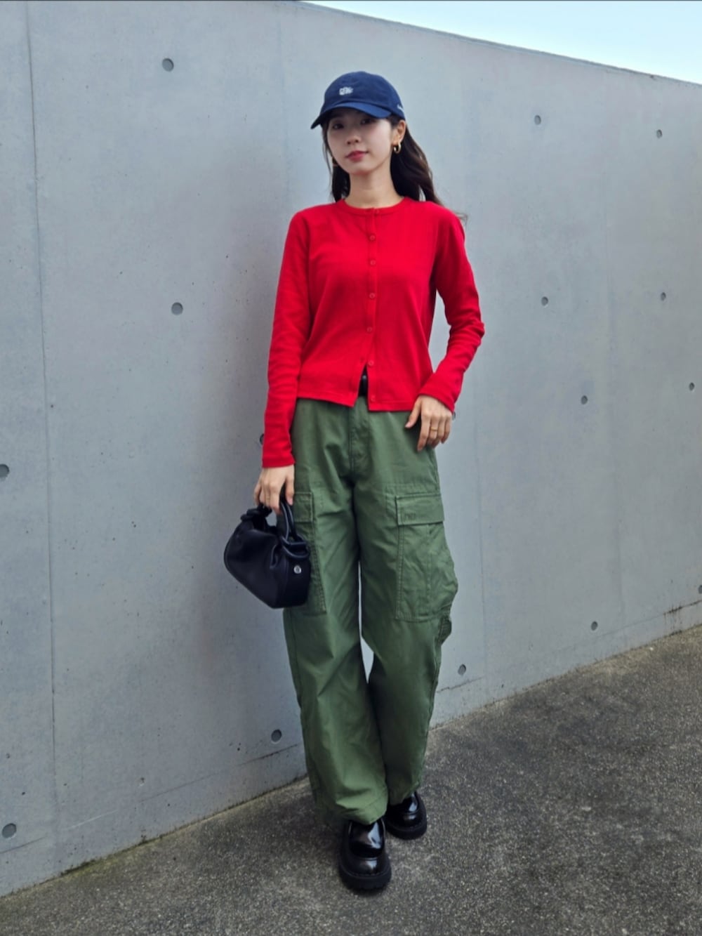 グリーン系のカーゴパンツ、レッド系のカーディガン/ボレロ、ブラック系のハンドバッグを着用したレディースの春コーディネートの3枚目の写真