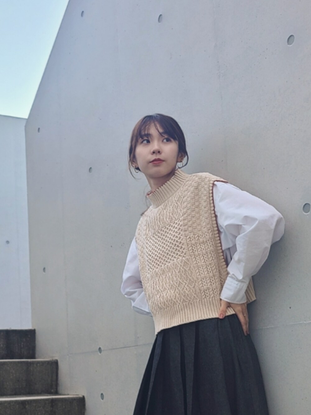 ベージュ系のベスト、ブラック系のデニムスカート、ブラック系のブーツを着用したレディースの秋コーディネートの3枚目の写真