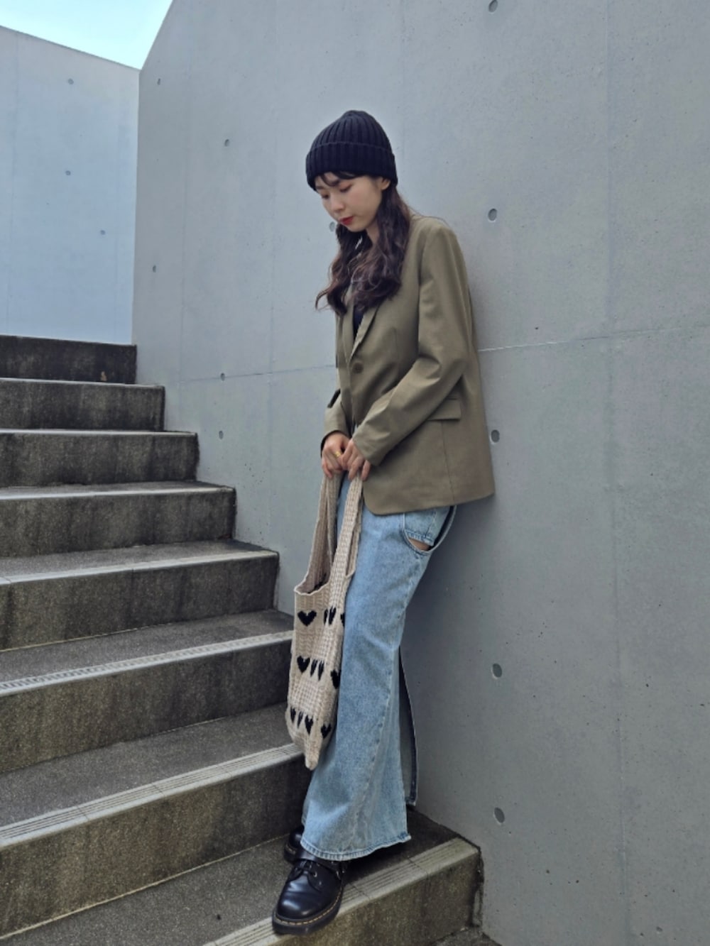 ベージュ系のトートバッグ、グリーン系のテーラードジャケット、ブルー系のデニムスカートを着用したレディースの秋コーディネートの4枚目の写真