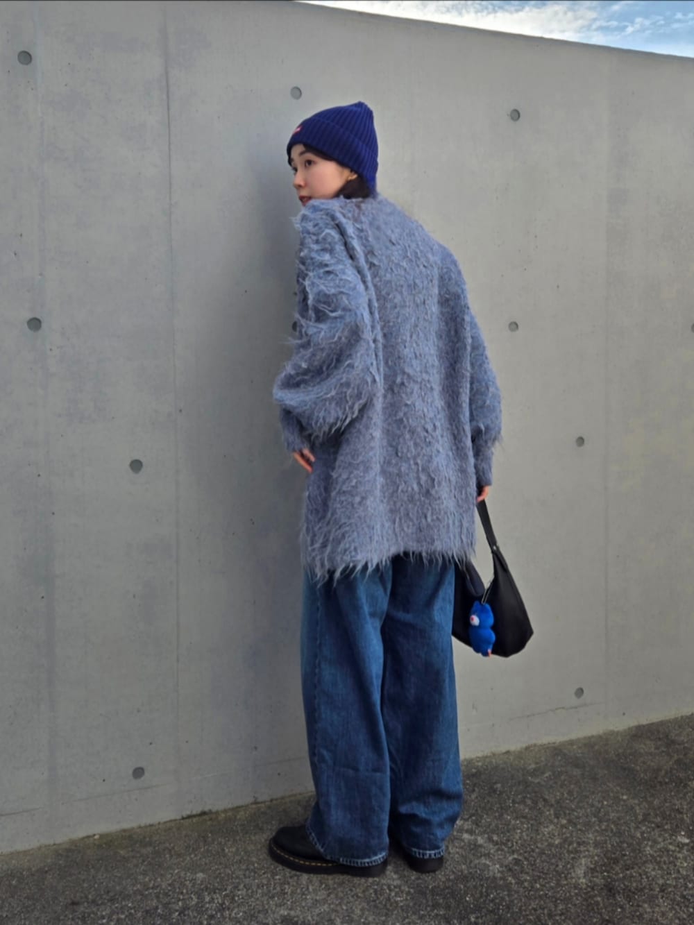 ブルー系のカーディガン/ボレロ、ブラック系のハンドバッグ、ブルー系のデニムパンツを着用したレディースの秋コーディネートの5枚目の写真