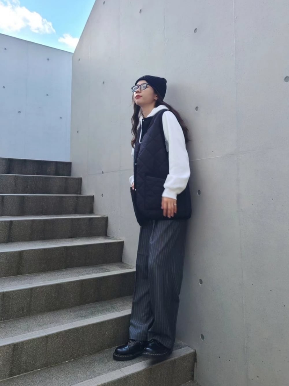 ブラック系のベスト、グレー系のスラックス、ブラック系のブーツを着用したレディースの秋コーディネートの3枚目の写真