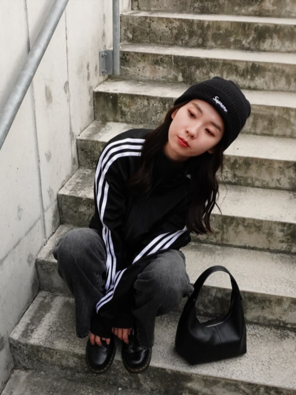 グレー系のデニムパンツ、ブラック系のハンドバッグ、ブラック系のジャージを着用したレディースの秋コーディネートの5枚目の写真