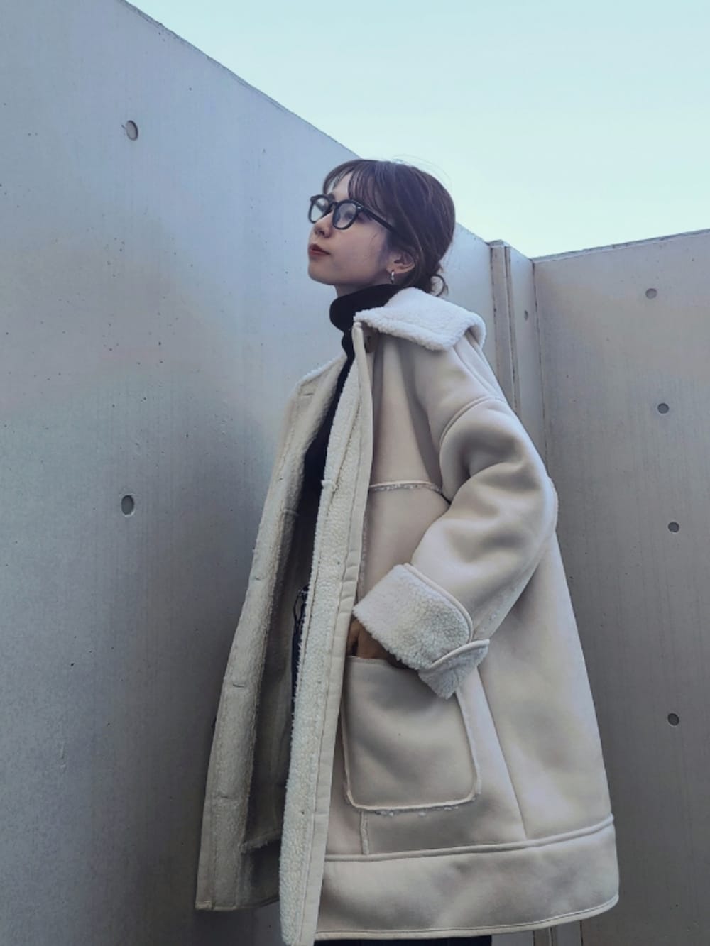 ブルー系のデニムパンツ、ブラック系のブーツ、ホワイト系のムートンコートを着用したレディースの秋コーディネートの2枚目の写真