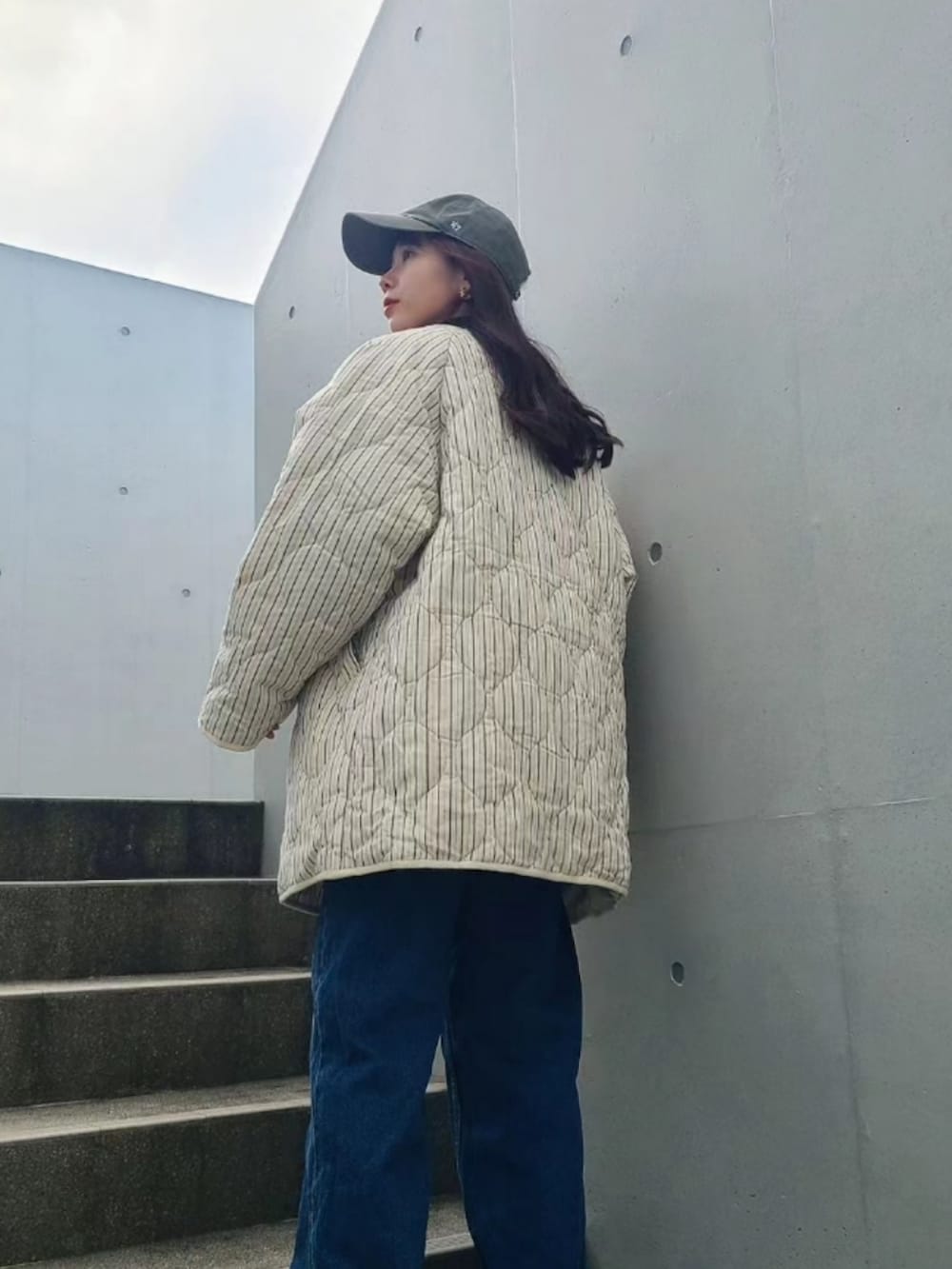 ブルー系のデニムパンツ、ブラック系のブーツ、ホワイト系のノーカラージャケットを着用したレディースの冬コーディネートの2枚目の写真