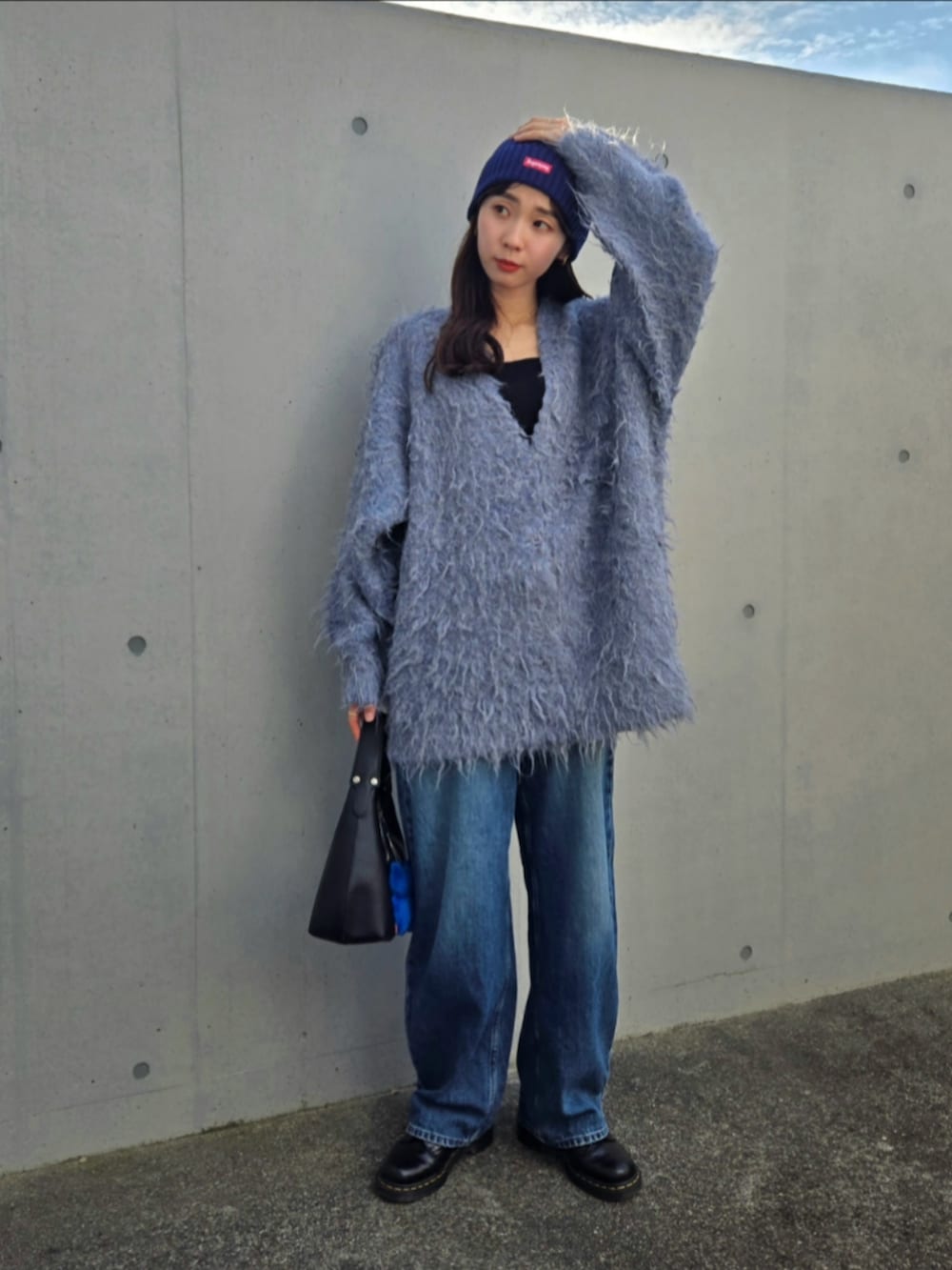 ブルー系のカーディガン/ボレロ、ブラック系のハンドバッグ、ブルー系のデニムパンツを着用したレディースの秋コーディネートの2枚目の写真