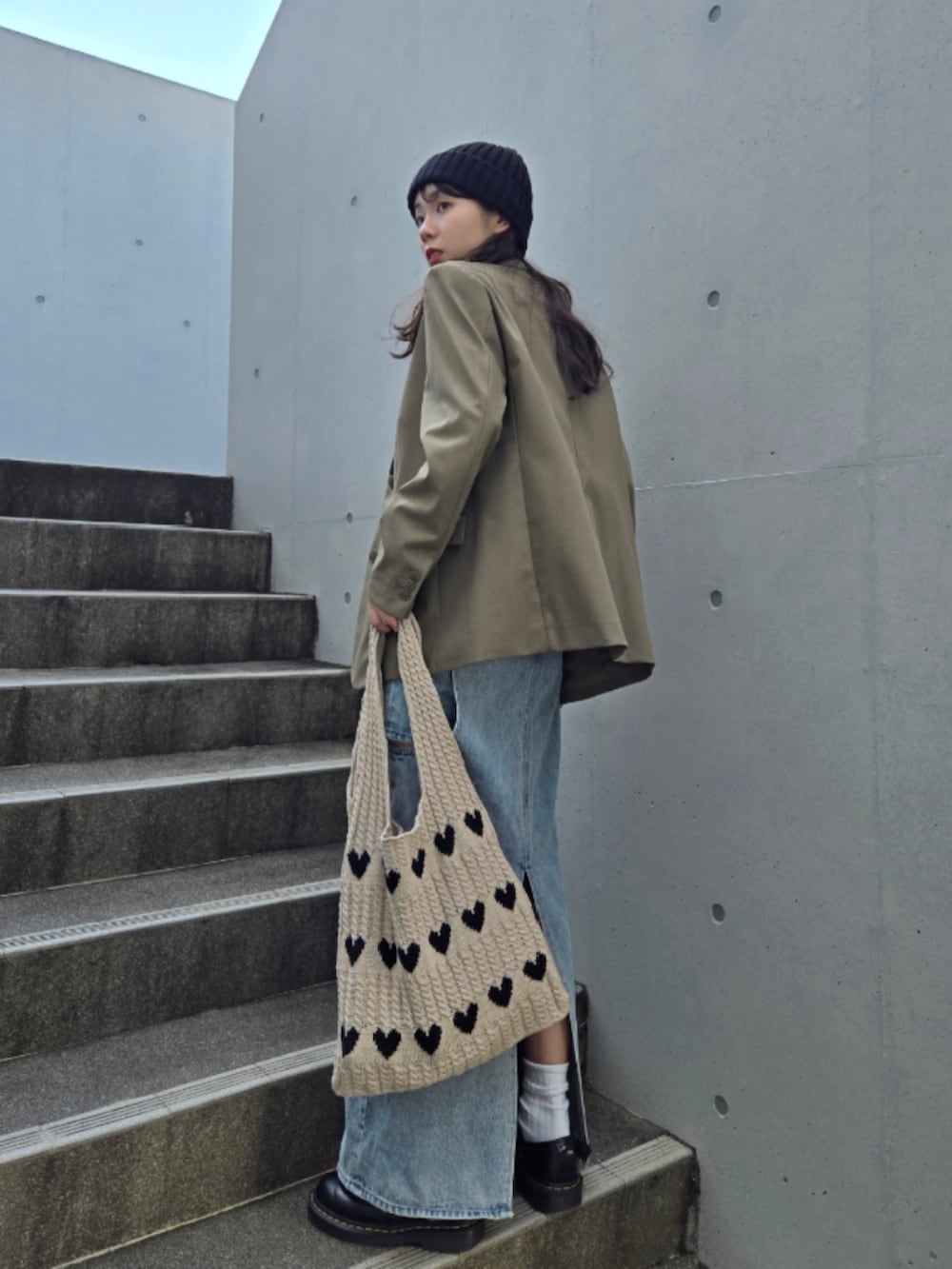 ベージュ系のトートバッグ、グリーン系のテーラードジャケット、ブルー系のデニムスカートを着用したレディースの秋コーディネートの2枚目の写真