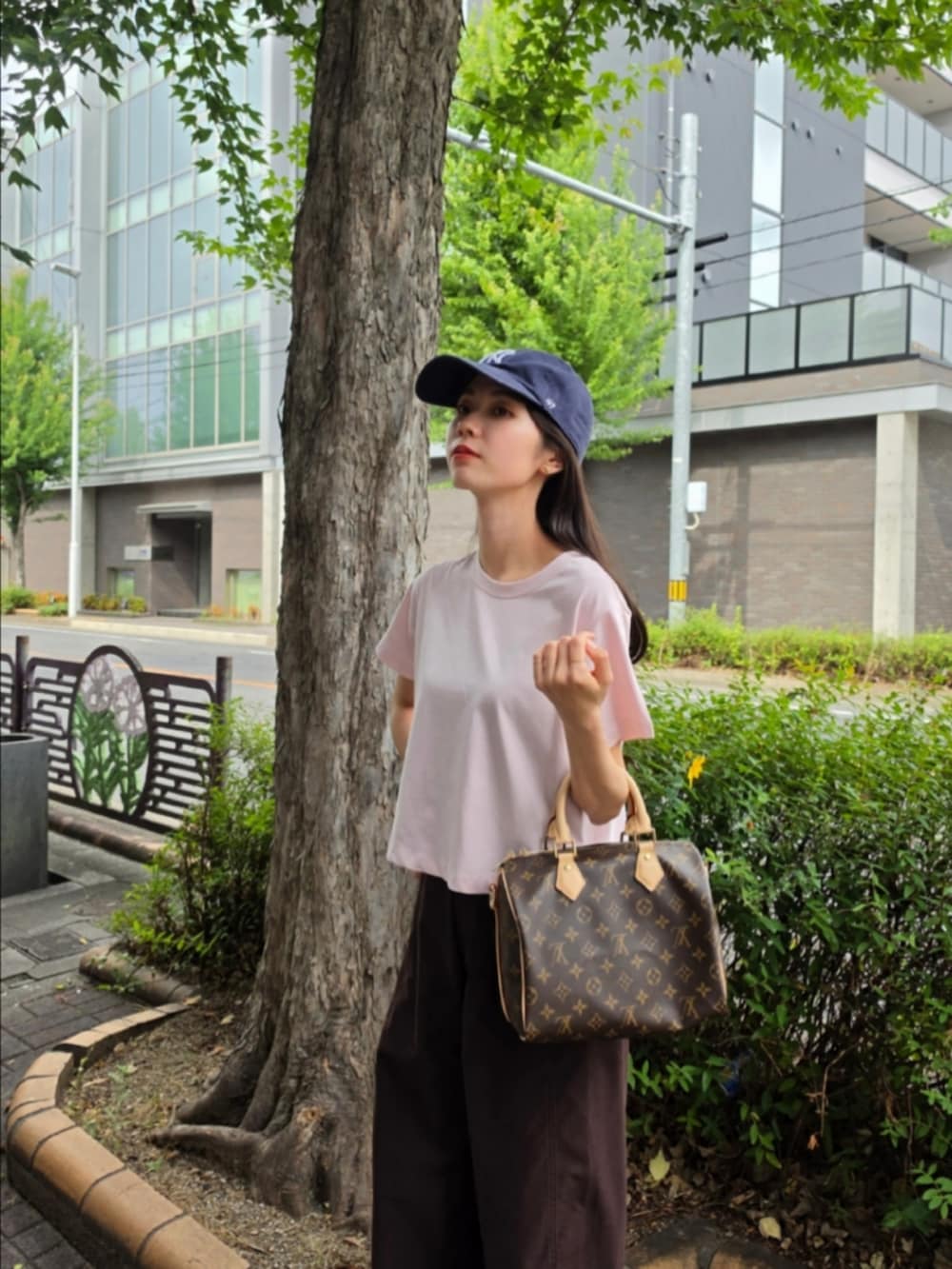 ピンク系のTシャツ/カットソー、ブラウン系のボストンバッグ、ブラウン系のパンツを着用したレディースの夏コーディネートの2枚目の写真