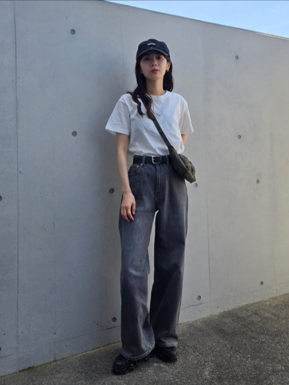 ピンク系のタンクトップ、グレー系のデニムパンツ、ブラック系のスニーカーを着用したレディースの春コーディネートの2枚目の写真