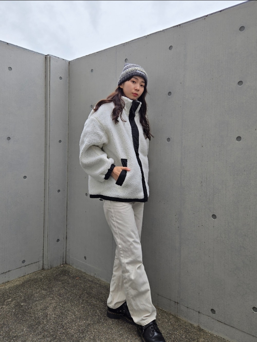 ブラック系のブルゾン、ホワイト系のデニムパンツ、ブラック系のブーツを着用したレディースの秋コーディネートの4枚目の写真