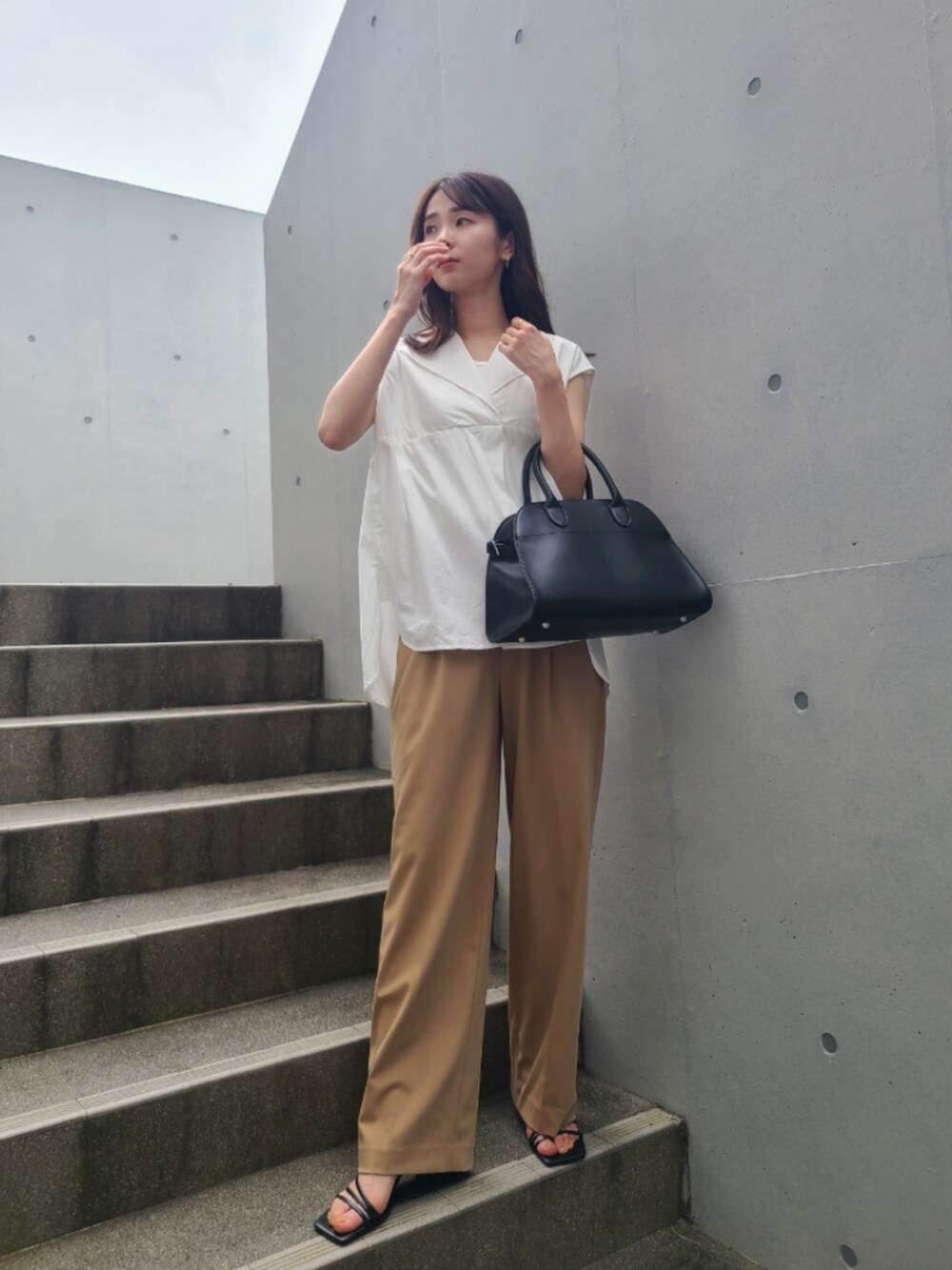 ブラック系のサンダル、ベージュ系のパンツ、ブラック系のボストンバッグを着用したレディースの夏コーディネートの3枚目の写真