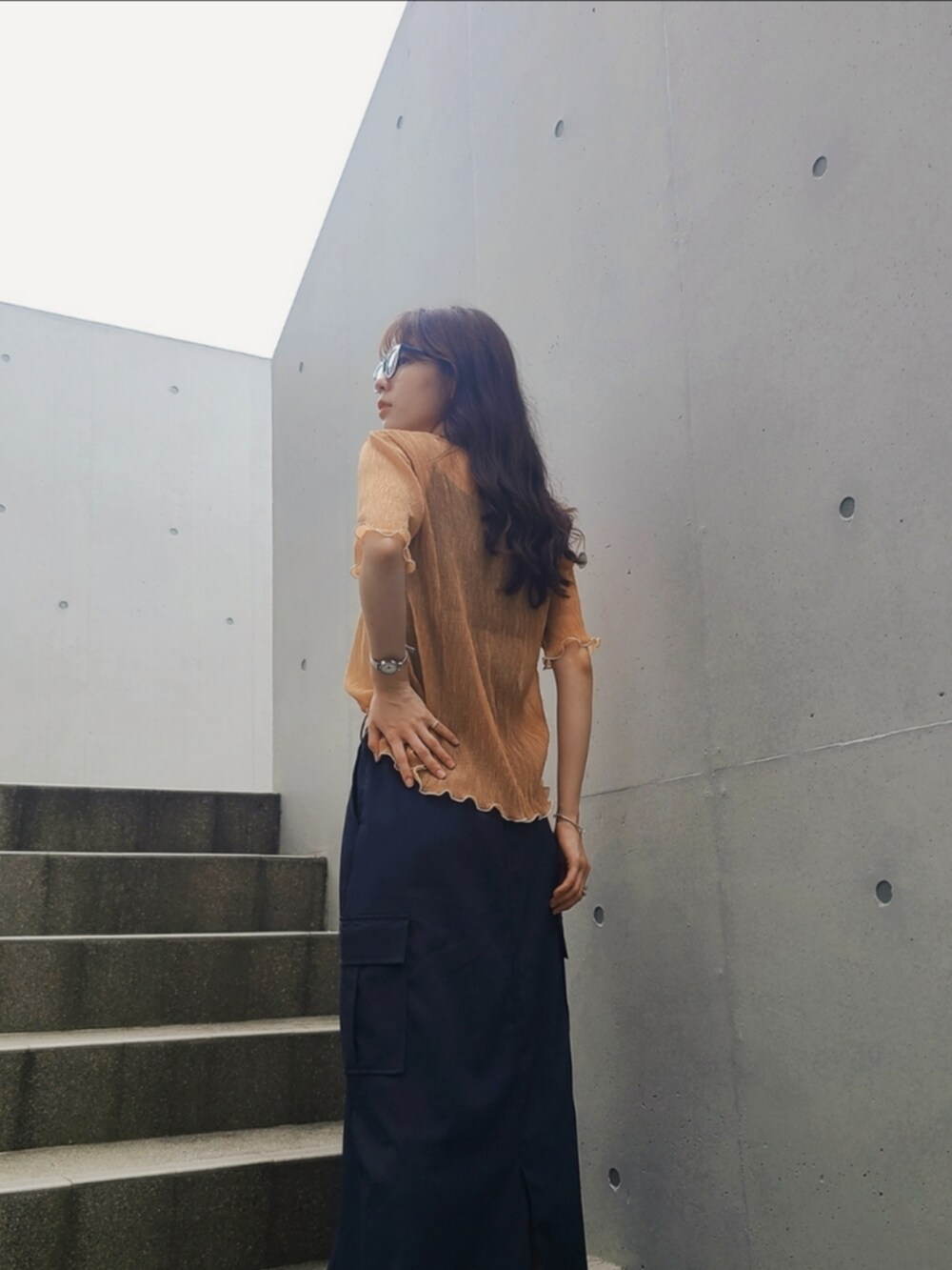 オレンジ系のシャツ/ブラウス、ブルー系のスカート、シルバー系のピアス（両耳用）を着用したレディースの夏コーディネートの3枚目の写真