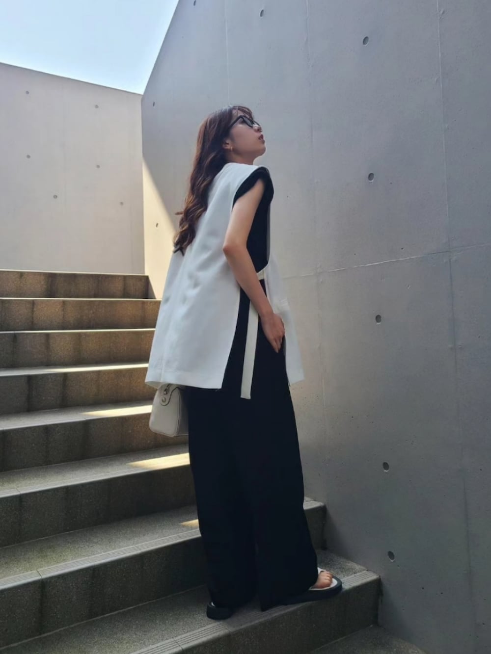 ブラック系のその他パンツ、ブラック系のTシャツ/カットソー、ホワイト系のサンダルを着用したレディースの夏コーディネートの3枚目の写真