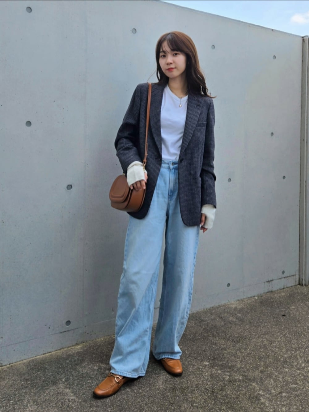 グレー系のテーラードジャケット、ブルー系のデニムパンツ、ブラウン系のシューズを着用したレディースの秋コーディネートの3枚目の写真