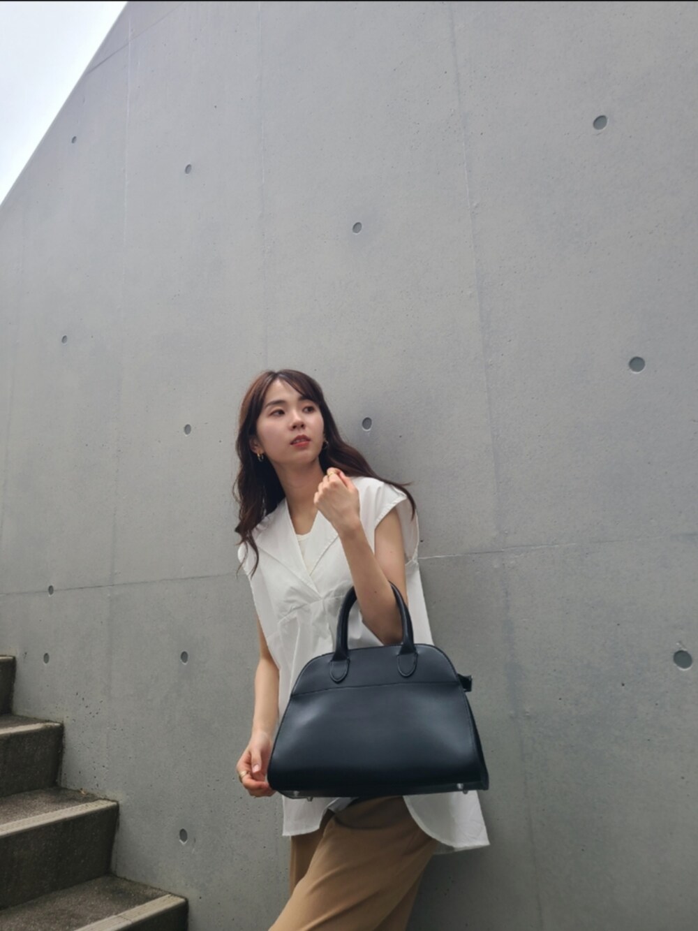 ブラック系のサンダル、ベージュ系のパンツ、ブラック系のボストンバッグを着用したレディースの夏コーディネートの2枚目の写真