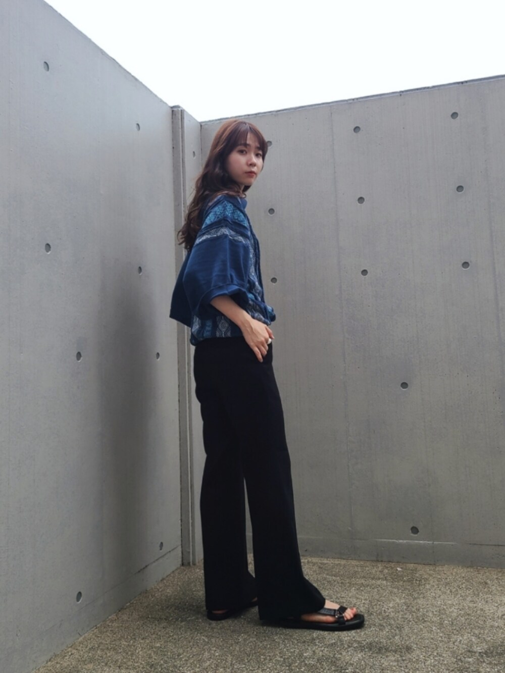 ブルー系のポロシャツ、ブラック系のパンツ、ブラック系のサンダルを着用したレディースの夏コーディネートの3枚目の写真