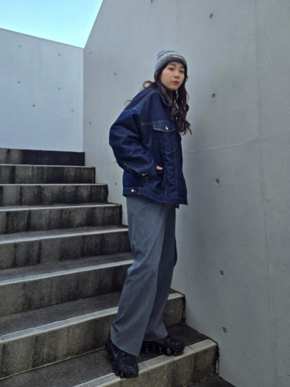 ブルー系のデニムジャケット、グレー系のパンツ、ブラック系のスニーカーを着用したレディースの冬コーディネートの3枚目の写真