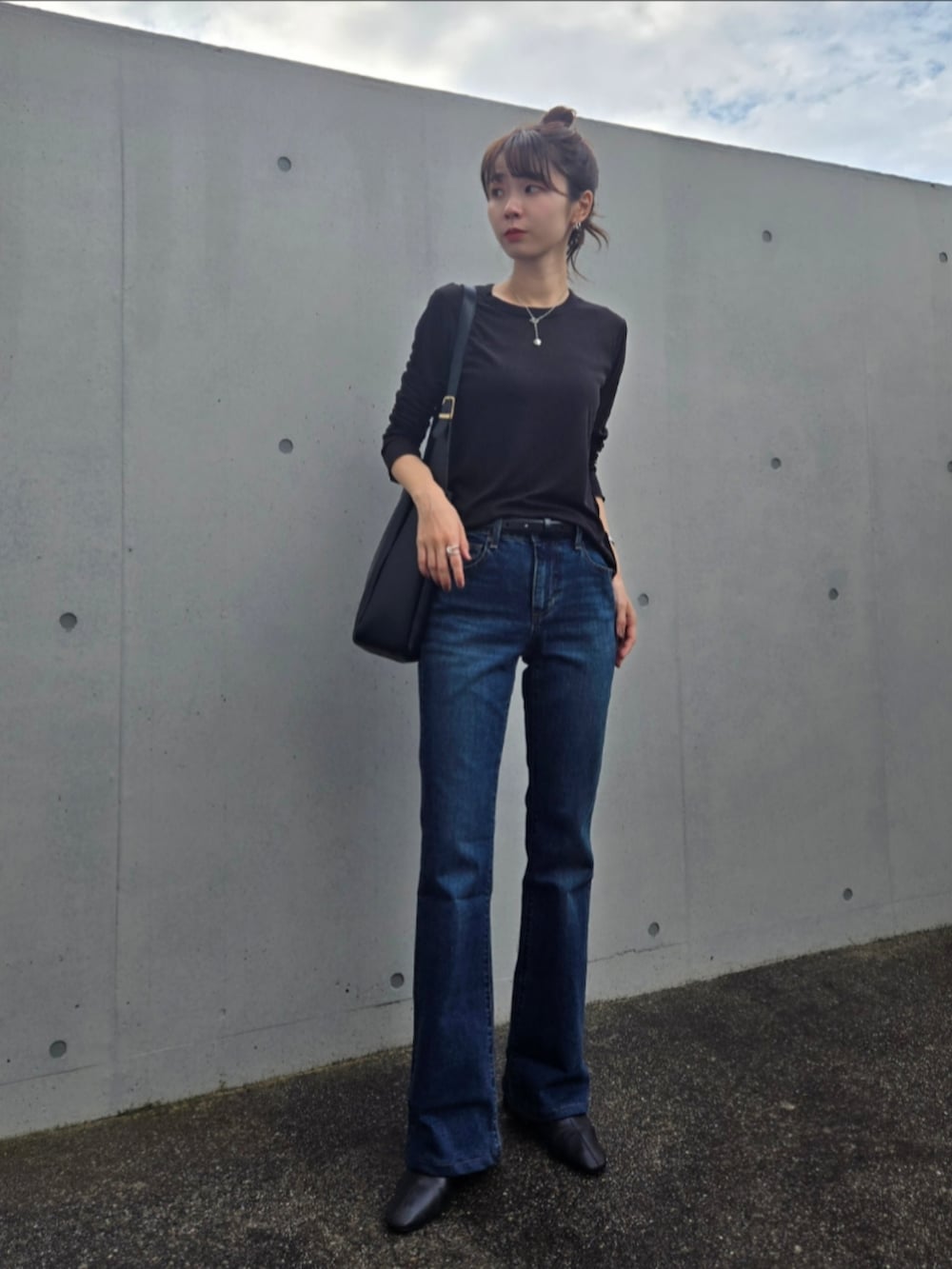 ブラック系のTシャツ/カットソー、ブルー系のデニムパンツ、ブラック系のブーツを着用したレディースの秋コーディネートの2枚目の写真