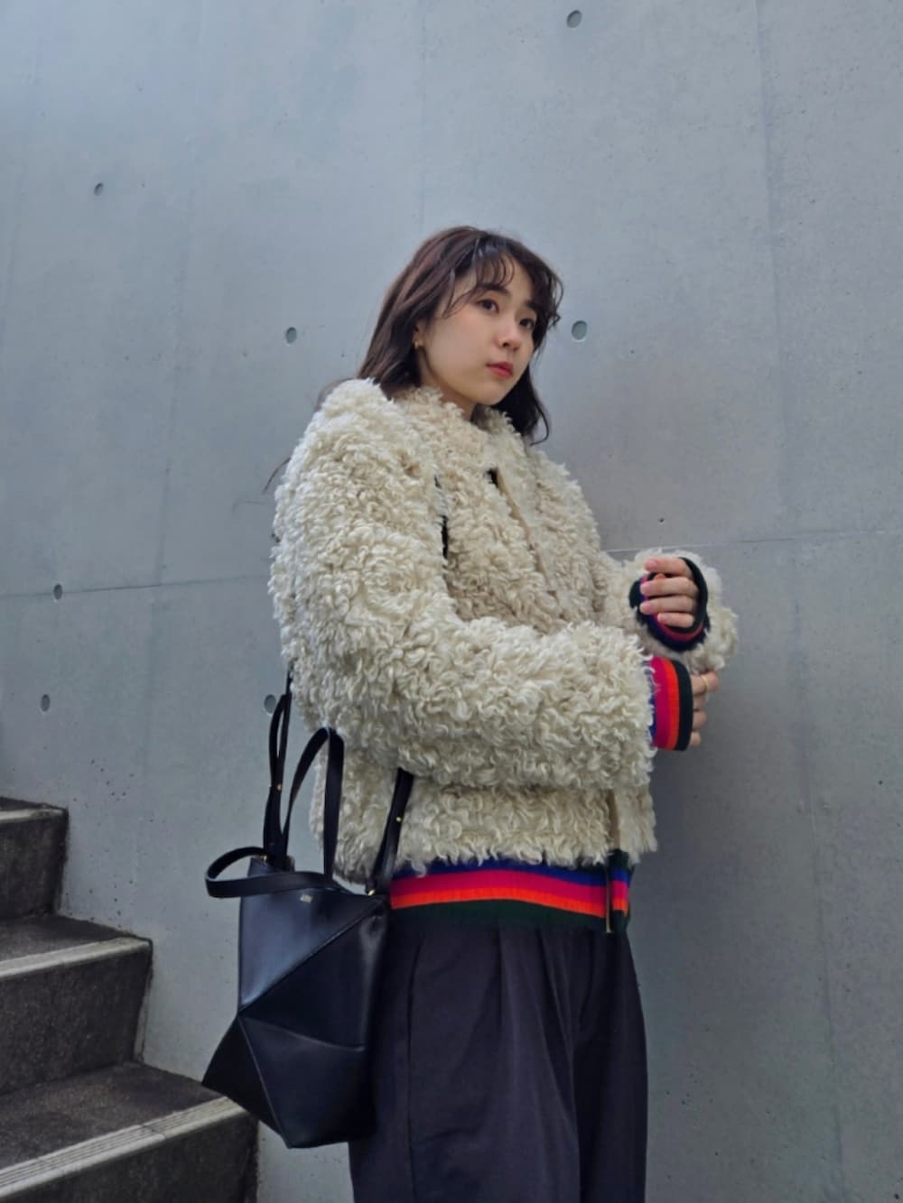 ベージュ系のブルゾン、ブラック系のトートバッグ、グレー系のスラックスを着用したレディースの冬コーディネートの2枚目の写真