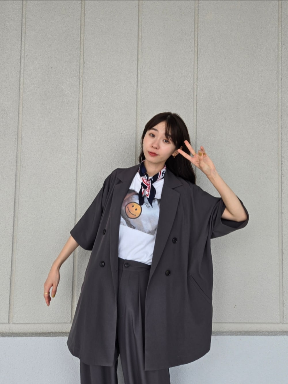 ブラック系のサンダル、ブラウン系のかごバッグ、グレー系のテーラードジャケットを着用したレディースの秋コーディネートの4枚目の写真