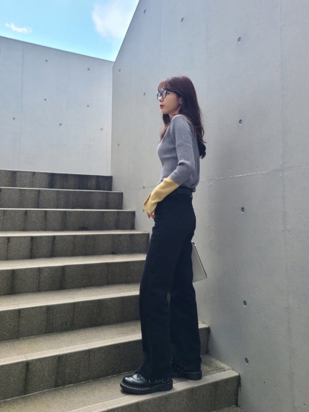 グレー系のニット/セーター、ブラック系のブーツ、ブラック系のデニムパンツを着用したレディースの秋コーディネートの2枚目の写真
