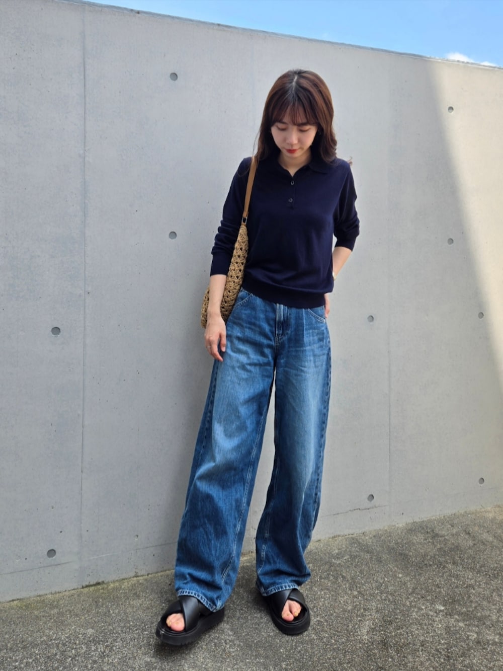 ブラウン系のかごバッグ、ブルー系のニット/セーター、ブルー系のデニムパンツを着用したレディースの夏コーディネートの3枚目の写真