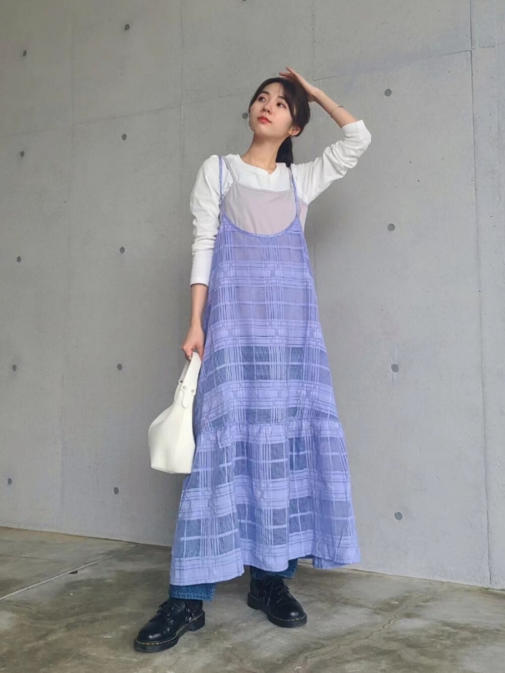 ホワイト系のハンドバッグ、ブラック系のブーツ、ブルー系のデニムパンツを着用したレディースの春コーディネートの2枚目の写真