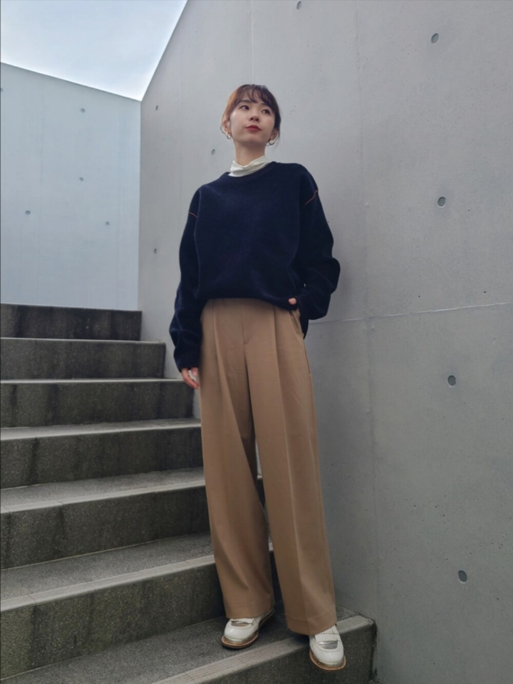 ブルー系のニット/セーター、ベージュ系のパンツ、ホワイト系のその他シューズを着用したレディースの冬コーディネートの2枚目の写真