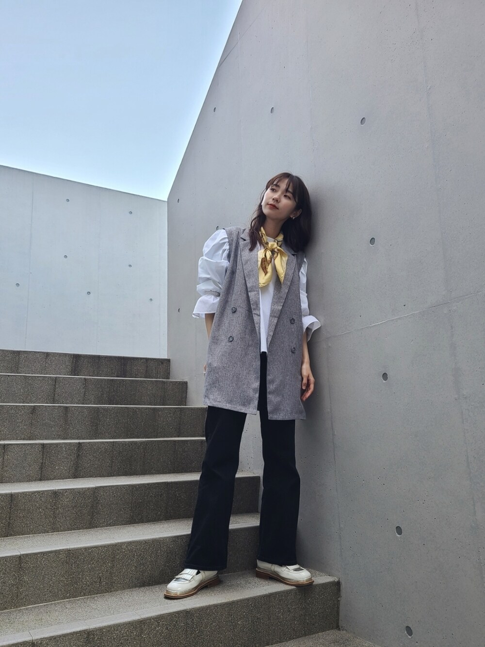 グレー系のベスト、ホワイト系のシャツ/ブラウス、ブラック系のデニムパンツを着用したレディースの春コーディネートの2枚目の写真