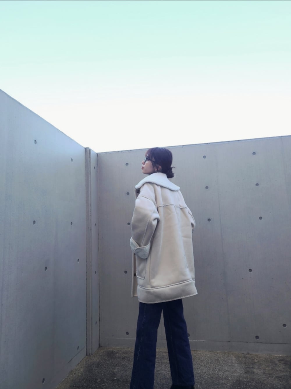 ブルー系のデニムパンツ、ブラック系のブーツ、ホワイト系のムートンコートを着用したレディースの秋コーディネートの3枚目の写真