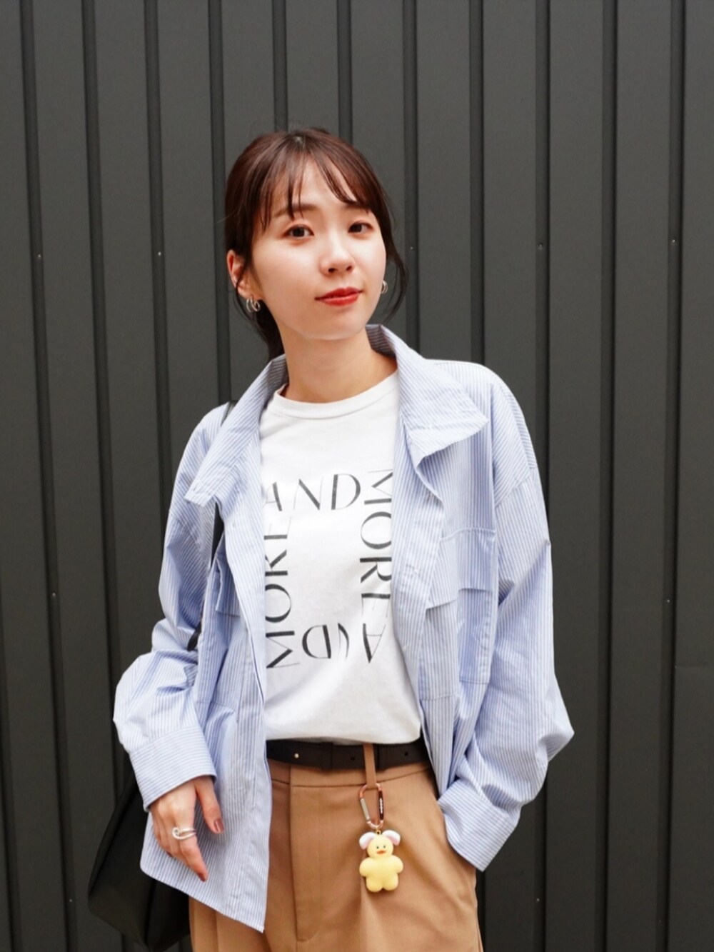 ベージュ系のパンツ、ブラック系のトートバッグ、ホワイト系のTシャツ/カットソーを着用したレディースの秋コーディネートの2枚目の写真