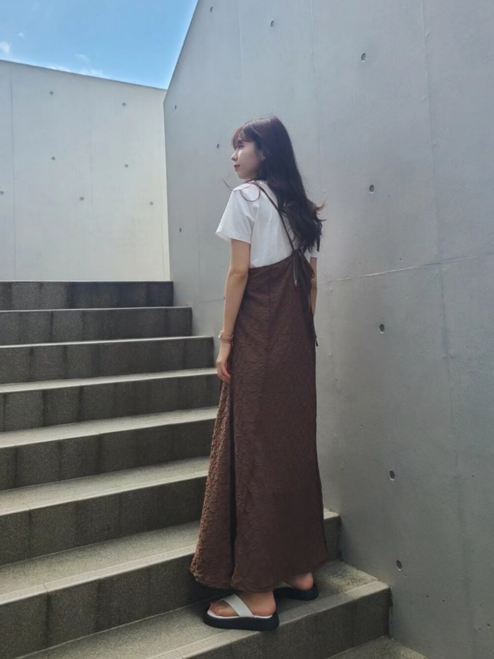 ホワイト系のサンダル、ブラウン系のワンピース、ゴールド系のネックレスを着用したレディースの夏コーディネートの2枚目の写真