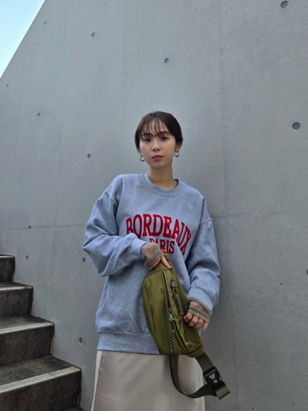 ブラック系のブーツ、ホワイト系のスカート、グリーン系のボディバッグ/ウエストポーチを着用したレディースの秋コーディネートの2枚目の写真