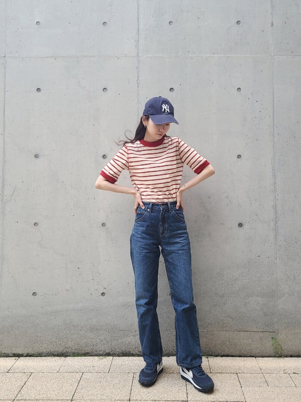 レッド系のTシャツ/カットソー、ブルー系のデニムパンツ、ブルー系のスニーカーを着用したレディースの春コーディネートの3枚目の写真