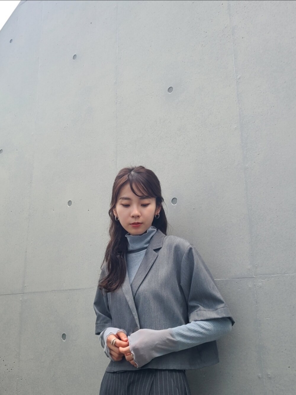 グレー系のスラックス、グレー系のセットアップ、ブルー系のTシャツ/カットソーを着用したレディースの秋コーディネートの2枚目の写真