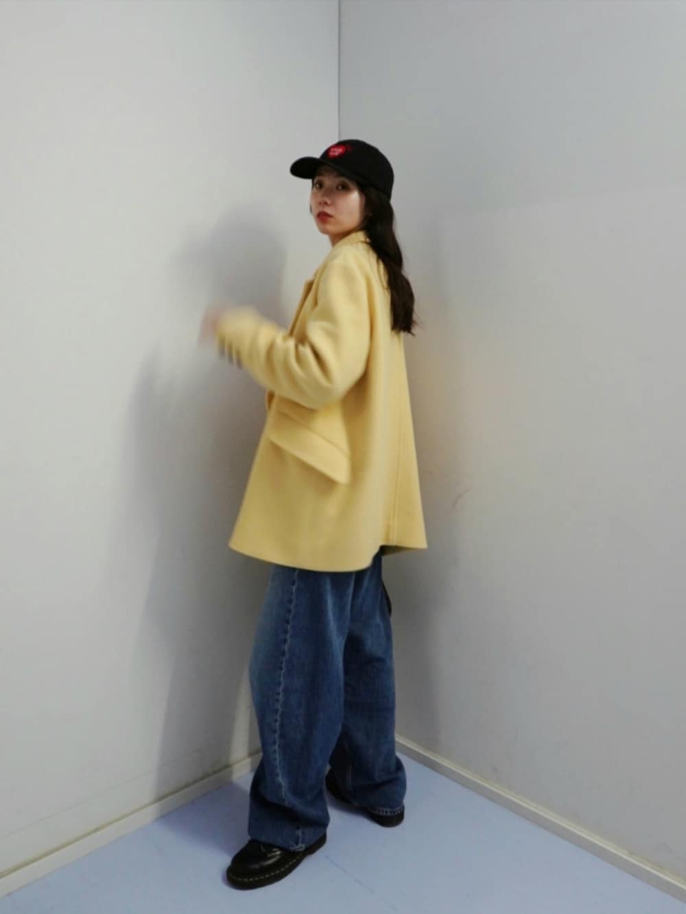 ブラック系のハンドバッグ、ブルー系のデニムパンツ、イエロー系のジャケット/アウターを着用したレディースの冬コーディネートの3枚目の写真